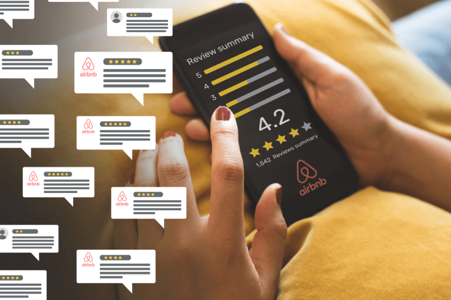 Close-up of a person's hand holding a smartphone displaying Airbnb review summary with a 4.2-star rating out of 1,542 reviews, surrounded by speech bubbles with various star ratings.